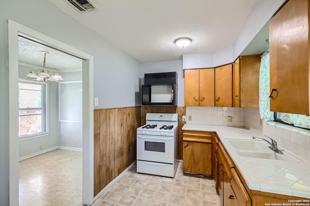 kitchen featuring sink, a chandelier, tile counters, white range with gas cooktop, and pendant lighting