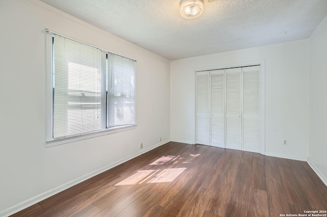 unfurnished bedroom with dark wood-type flooring, a closet, and a textured ceiling