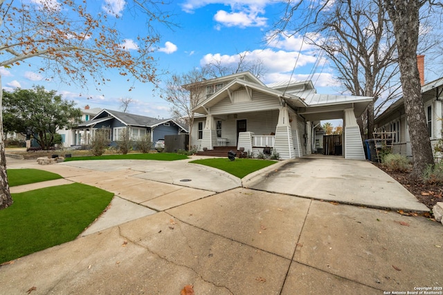 view of front of home with a front yard, a carport, and a porch