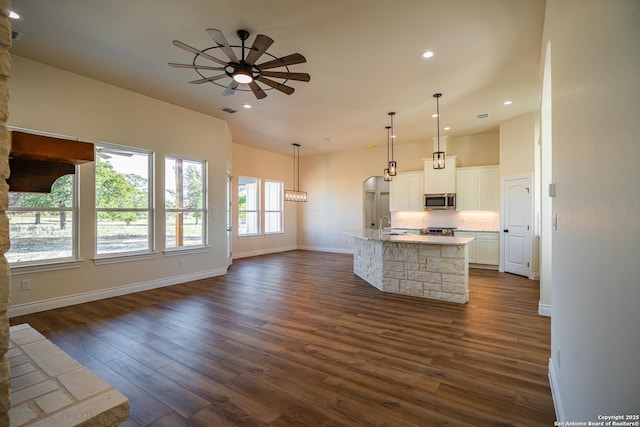 kitchen with ceiling fan, white cabinetry, dark hardwood / wood-style floors, a spacious island, and decorative light fixtures