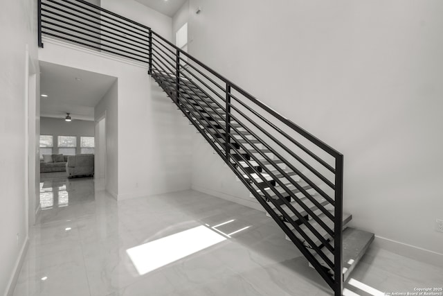 staircase with ceiling fan and a high ceiling