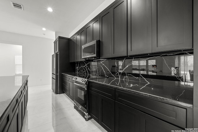 kitchen with tasteful backsplash, appliances with stainless steel finishes, and dark stone counters