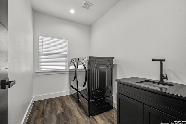 laundry area with sink, dark wood-type flooring, washer and clothes dryer, and cabinets