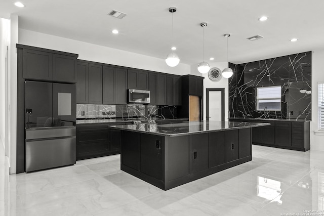 kitchen with a kitchen island, decorative light fixtures, dark stone countertops, backsplash, and fridge