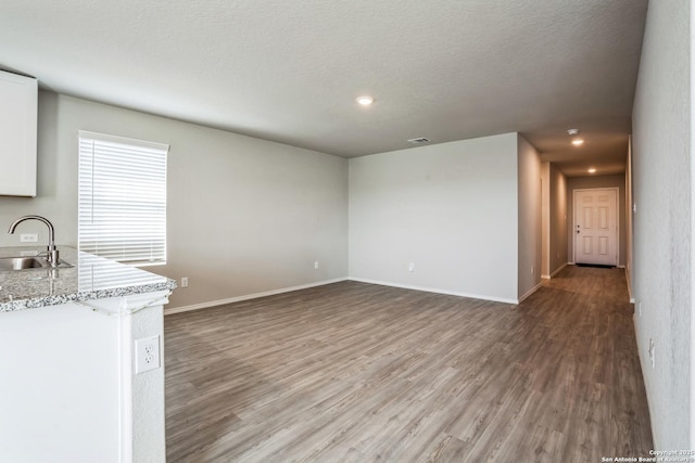 unfurnished living room featuring hardwood / wood-style flooring, sink, and a textured ceiling