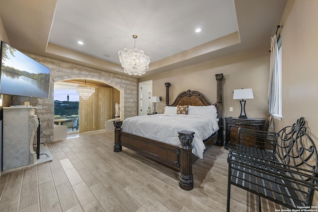 bedroom featuring a notable chandelier and a tray ceiling