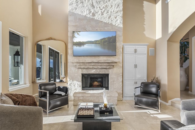 tiled living room featuring a high ceiling and a fireplace