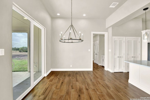 unfurnished dining area with dark hardwood / wood-style floors and an inviting chandelier