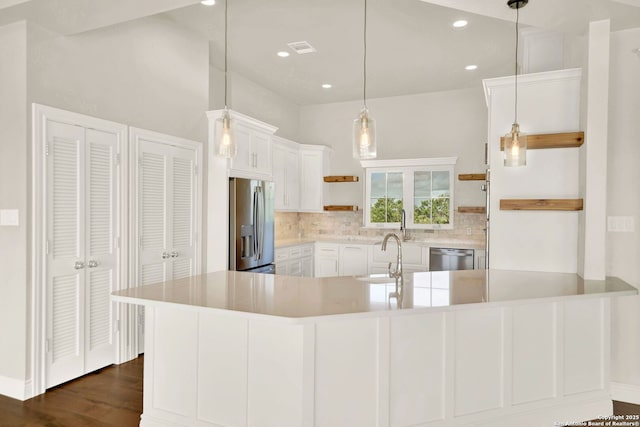 kitchen with appliances with stainless steel finishes, sink, white cabinets, backsplash, and hanging light fixtures