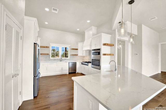 kitchen with sink, appliances with stainless steel finishes, white cabinetry, light stone countertops, and decorative light fixtures