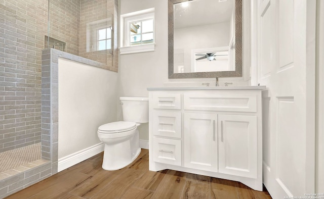 bathroom with vanity, hardwood / wood-style floors, toilet, and tiled shower