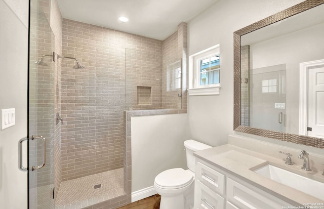 bathroom featuring walk in shower, wood-type flooring, vanity, and toilet