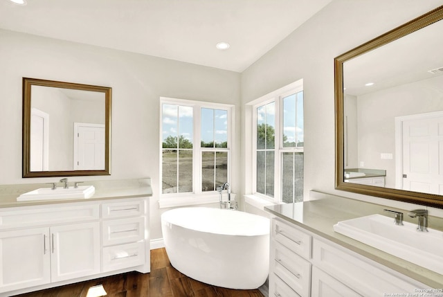 bathroom featuring vanity, hardwood / wood-style floors, and a tub