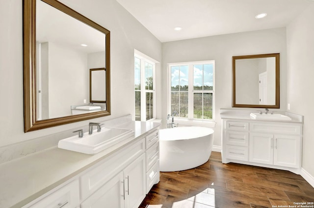 bathroom featuring hardwood / wood-style flooring, vanity, and a bath