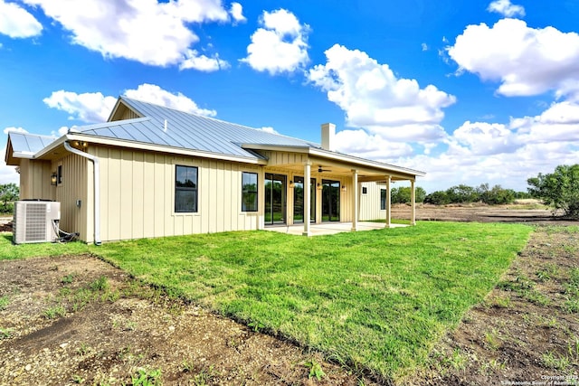 back of property with central AC, a patio, and a lawn