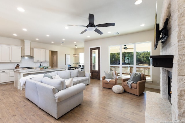 living room with a fireplace, light hardwood / wood-style floors, and ceiling fan