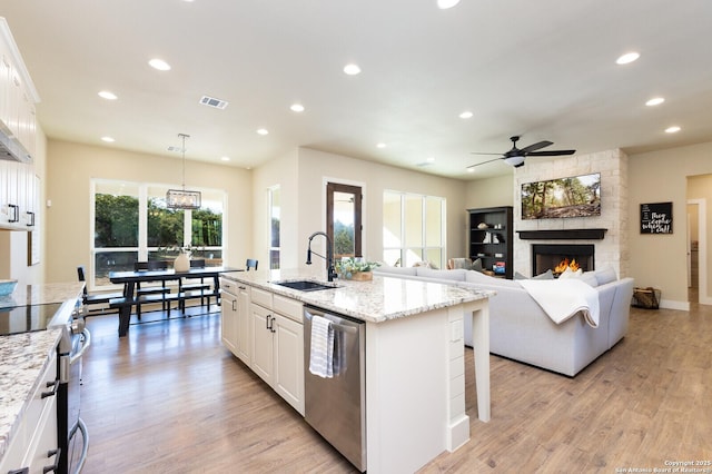 kitchen featuring pendant lighting, sink, a kitchen island with sink, stainless steel appliances, and white cabinets