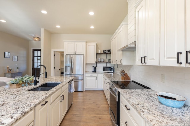 kitchen with sink, white cabinetry, stainless steel appliances, light hardwood / wood-style floors, and light stone countertops