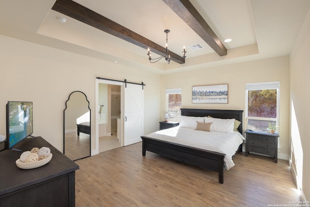 bedroom featuring light hardwood / wood-style flooring, an inviting chandelier, beam ceiling, a raised ceiling, and a barn door