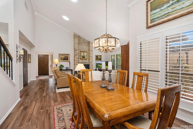 dining space with ornamental molding, high vaulted ceiling, dark wood-type flooring, and an inviting chandelier