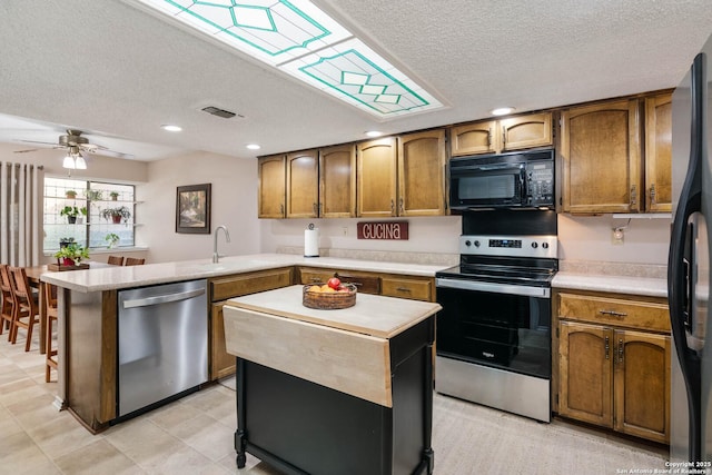 kitchen with stainless steel appliances, kitchen peninsula, a textured ceiling, and a center island