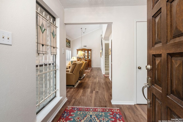 entryway featuring crown molding, dark hardwood / wood-style flooring, vaulted ceiling, and a textured ceiling