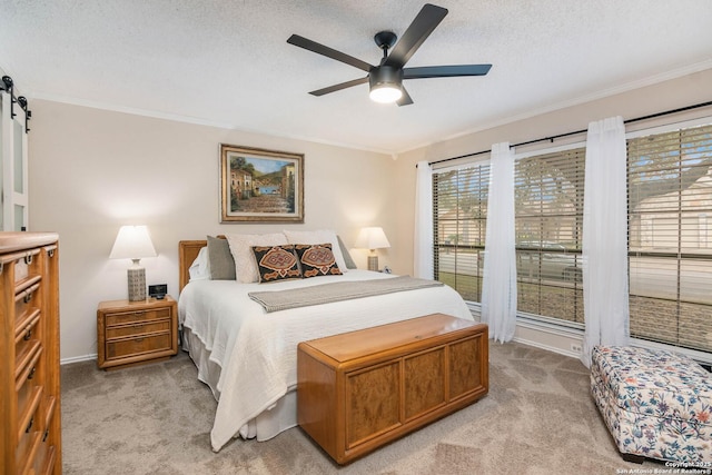 bedroom with a textured ceiling, light colored carpet, a barn door, and ceiling fan