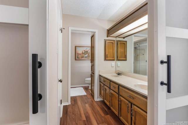 bathroom featuring wood-type flooring, toilet, a textured ceiling, and vanity