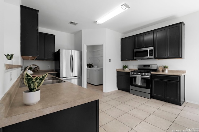 kitchen featuring sink, light tile patterned flooring, independent washer and dryer, and appliances with stainless steel finishes