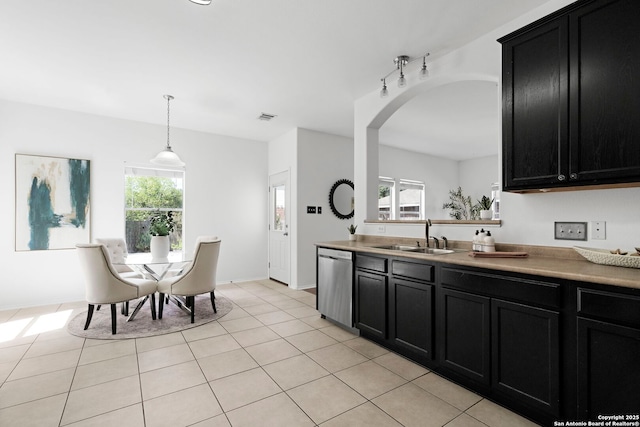 kitchen featuring stainless steel dishwasher, a healthy amount of sunlight, sink, and hanging light fixtures