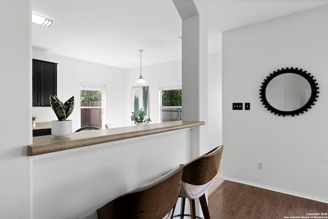 kitchen with a kitchen breakfast bar, dark hardwood / wood-style flooring, and decorative light fixtures