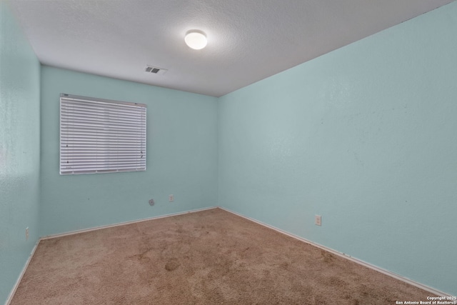 empty room with carpet floors and a textured ceiling