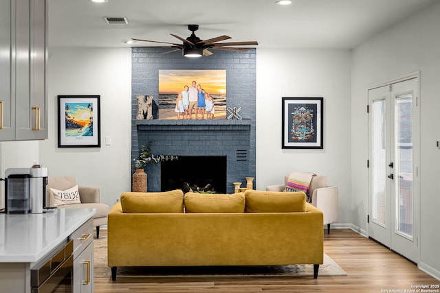 living room with ceiling fan, a fireplace, and light hardwood / wood-style floors