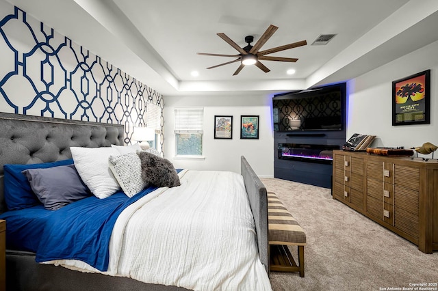 carpeted bedroom featuring a raised ceiling and ceiling fan