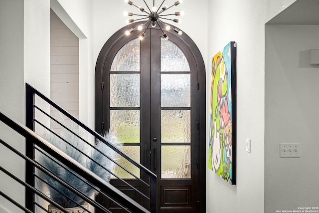 foyer entrance featuring a healthy amount of sunlight, an inviting chandelier, and french doors