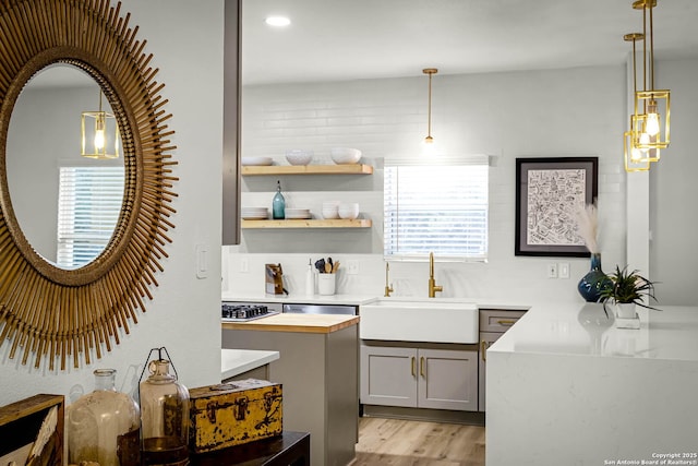 bar with sink, gray cabinets, pendant lighting, stainless steel appliances, and light hardwood / wood-style floors