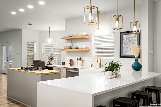 kitchen featuring pendant lighting, light hardwood / wood-style flooring, stainless steel appliances, and a kitchen bar