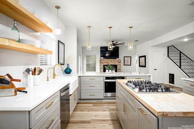 kitchen with appliances with stainless steel finishes, a center island, gray cabinetry, and pendant lighting