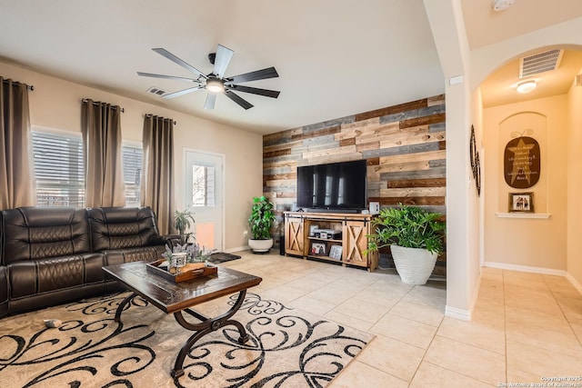 tiled living room with ceiling fan, plenty of natural light, and wooden walls