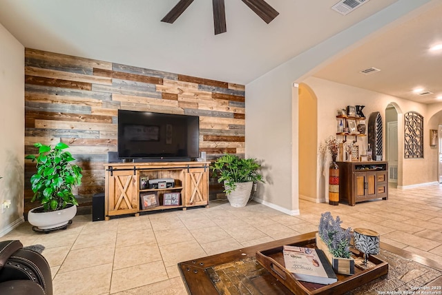 tiled living room featuring ceiling fan and wood walls