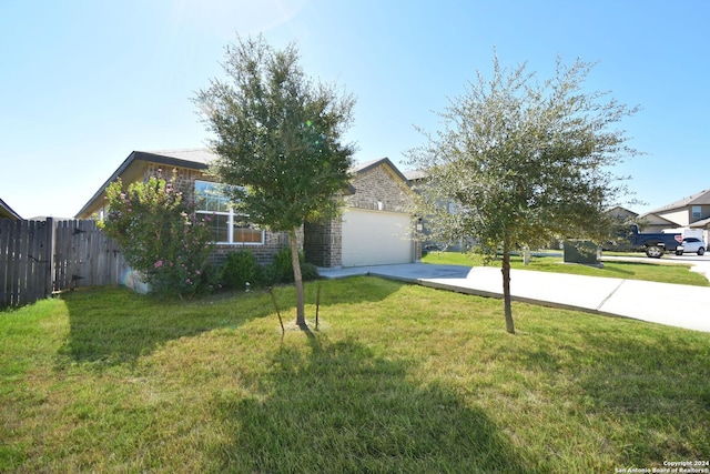 view of property hidden behind natural elements featuring a garage and a front yard