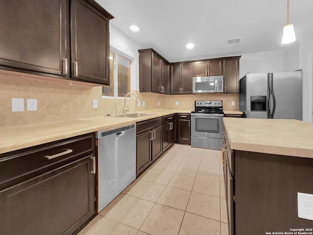 kitchen with pendant lighting, sink, light tile patterned floors, backsplash, and stainless steel appliances