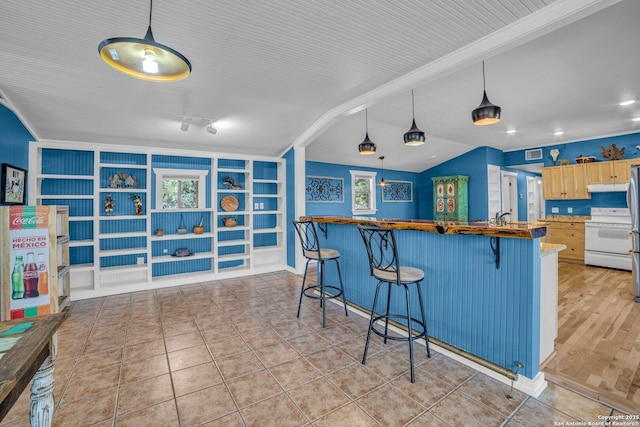 kitchen featuring built in shelves, light tile patterned flooring, light brown cabinetry, a breakfast bar, and white range with electric stovetop