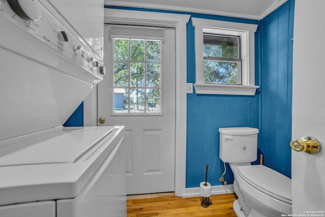 washroom featuring hardwood / wood-style flooring and stacked washer / dryer