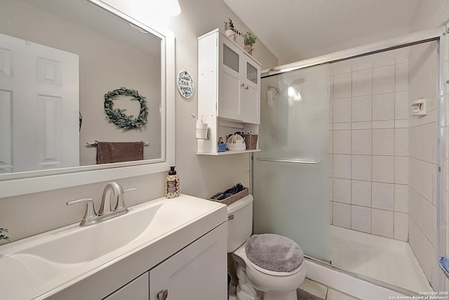 bathroom featuring vanity, a textured ceiling, a shower with shower door, and toilet