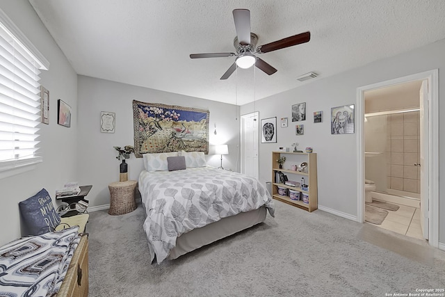 bedroom featuring light carpet, connected bathroom, a textured ceiling, and ceiling fan