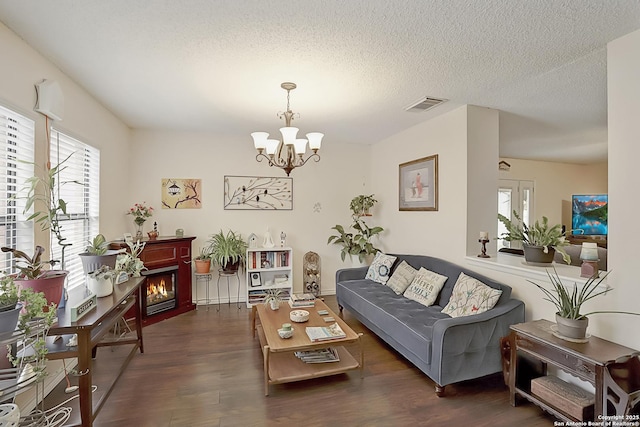 living room featuring dark hardwood / wood-style floors, a textured ceiling, and a notable chandelier