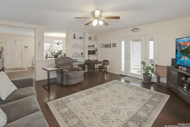 living room with dark hardwood / wood-style flooring and ceiling fan with notable chandelier