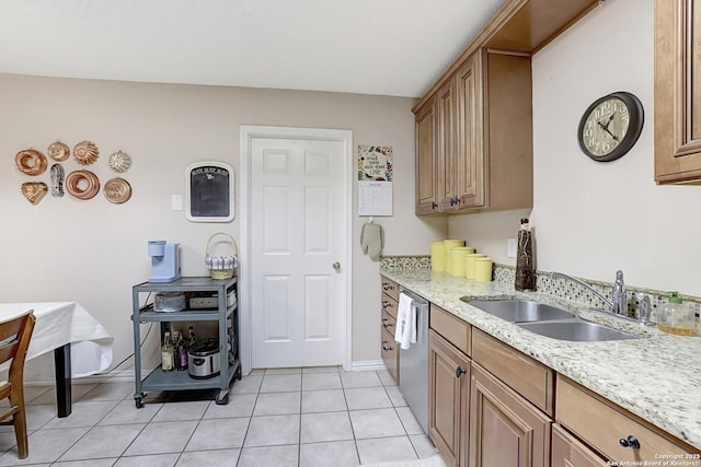 kitchen featuring light stone counters, sink, light tile patterned floors, and stainless steel dishwasher