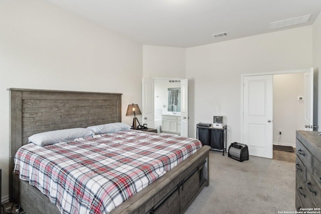 bedroom with connected bathroom and light carpet